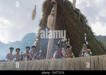 Immagine selettiva dei tribesmen di Naga vestiti in abiti tradizionali in piedi in una capanna Naga tradizionale a Kohima Nagaland India il 4 dicembre 2016 Foto Stock