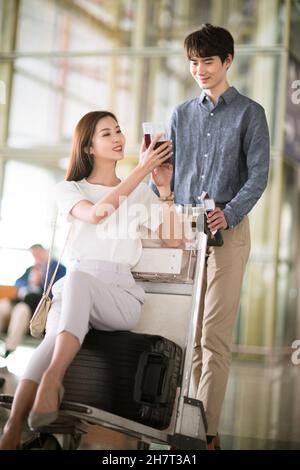 Giovane coppia che spinge i bagagli all'aeroporto Foto Stock