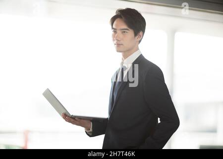 Giovane uomo d'affari che usa un computer portatile in una sala d'aeroporto Foto Stock