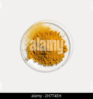 Primo piano ingrediente chimico cosmetico su tavola bianca da laboratorio. Curcuma organico in polvere in vetro da orologio chimico. Vista dall'alto Foto Stock