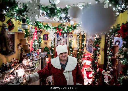 Oberhausen, Germania. 16 novembre 2021. Dirk van Acken si erge nel corridoio della sua casa vestita come Babbo Natale. L'uomo di Oberhausen sta decorando la sua casa per Natale dal 2013, e nel frattempo ha accumulato circa 30,000 luci dentro e intorno alla casa. Nessuna stanza nell'appartamento è senza decorazioni natalizie, e van Acken ha anche istituito due 'cannoni' nel giardino. Come le decorazioni di Natale sono cresciute, così ha fatto il numero di visitatori. Negli ultimi anni, quasi 1,000 visitatori hanno dato un'occhiata alla casa straordinaria. Credit: Fabian/dpa/Alamy Live News Foto Stock