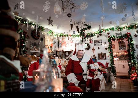 Oberhausen, Germania. 16 novembre 2021. Dirk van Acken siede nel suo soggiorno vestito come Babbo Natale. L'uomo di Oberhausen ha decorato il suo appartamento per Natale dal 2013, e nel frattempo ha accumulato circa 30,000 luci dentro e intorno alla casa. Nessuna stanza nell'appartamento è senza decorazioni natalizie, e van Acken ha anche istituito due 'cannoni' nel giardino. Come le decorazioni di Natale sono cresciute, così ha fatto il numero di visitatori. Negli ultimi anni, quasi 1,000 visitatori hanno dato un'occhiata alla casa straordinaria. Credit: Fabian Strau/dpa/Alamy Live News Foto Stock