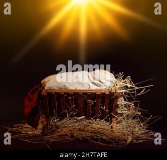 Mangiatoia con manichino di bambino su sfondo scuro. Concetto di storia di Natale Foto Stock