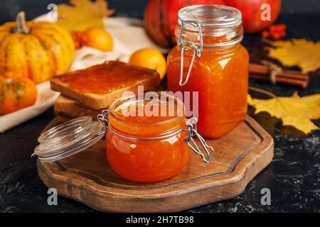 Vasetti di marmellata di zucca dolce e toast su sfondo nero Foto Stock