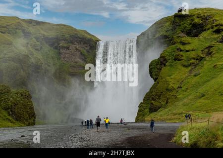 Vista dalla parte inferiore della cascata Seljalandsfoss in Islanda con la sua origine nel ghiacciaio del vulcano Eyjafjallajokull; numerose persone che camminano o Foto Stock
