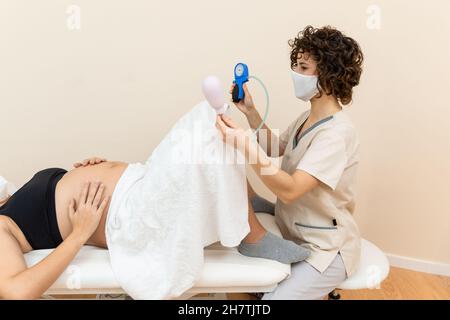 Ginecologo in possesso di un apparato muscolo pelvico del pavimento esercizio per preparare per la nascita di una donna sdraiata Foto Stock