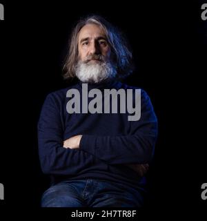 Ritratto di un anziano uomo portico grigio in abiti scuri su sfondo scuro. Il concetto è l'invecchiamento, la tristezza, la saggezza. Foto Stock