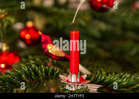 Erloschene rote Weihnachtskerze mit einer Rauchfahne an einem Weihnachtsbaum Foto Stock