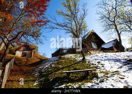 capanna di legno in una posizione appartata con alberi da frutta vecchi, tempo autunnale in montagna Foto Stock