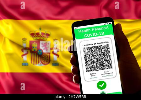 Spagna. 24 novembre 2021. In questa foto illustrativa un certificato simbolico di vaccino covid, chiamato anche passaporto covid, è visto sullo schermo di un telefono cellulare con la bandiera spagnola sullo sfondo a Barcellona, in Spagna, il 24 novembre 2021. L'attuazione del passaporto covid19 è in corso di discussione in varie regioni della Spagna dove il tasso di infezioni è in aumento. (Foto di Davide Bonaldo/Sipa USA) Credit: Sipa USA/Alamy Live News Foto Stock