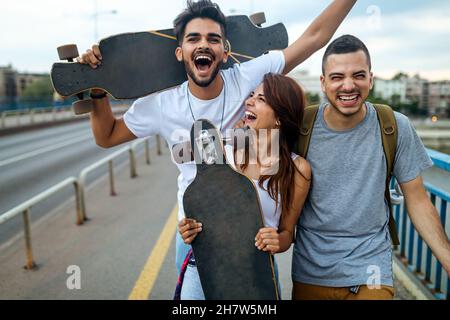 Ritratto di gente adolescente felice che si diverte mentre si guida uno skateboard in città all'aperto. Foto Stock