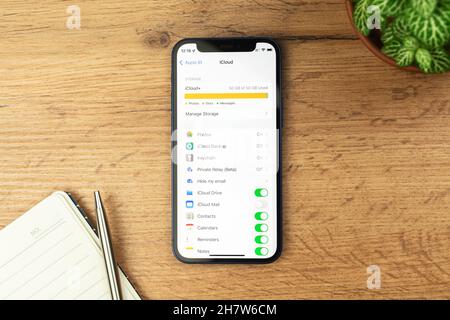 Kharkov, Ucraina - 21 novembre 2021: Schermata di impostazione iCloud su Apple iPhone. Sfondo tavola in legno Foto Stock