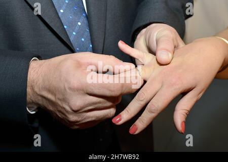 Anello d'oro che lo sposo mette sul dito della sposa sul suo giorno di nozze. Foto Stock