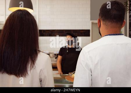 Coppia ordinando in caffetteria. Il personale della caffetteria serve il pubblico. Assistenza clienti. Clienti che ordinano in caffetteria. Foto Stock