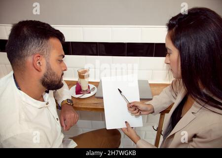 Coppia che controlla il loro lavoro. Coppia guardandosi l'un l'altro. Uomo e donna che rivedono i foglios. Meeting di lavoro. Foto Stock