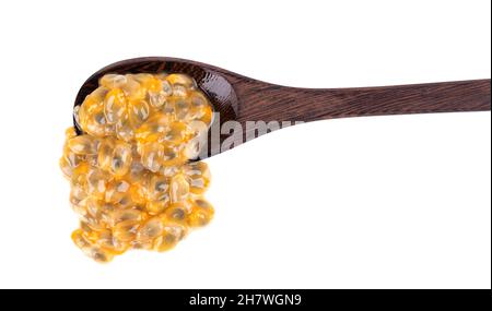 Semi di frutto della passione in cucchiaio di legno, isolato su sfondo bianco. Polpa di passionfrutto o maracuya, frutta esotica Foto Stock