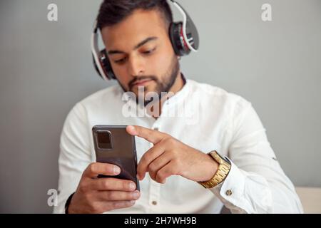 Ragazzo che ascolta musica con le cuffie. Uomo con cellulare. Uomo in un bar che guarda il mobile. Stile di vita. Pausa di lavoro. Foto Stock