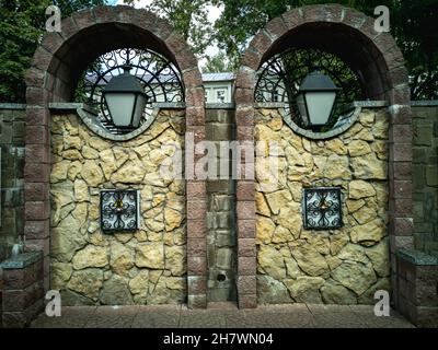 Archi in pietra decorativa con lampade per l'illuminazione stradale. Elementi architettonici. Foto orizzontale. Foto Stock