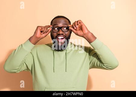 Ritratto di soddisfatto uomo felice braccia toccare occhiali guardare interessato spazio vuoto isolato su sfondo beige colore Foto Stock