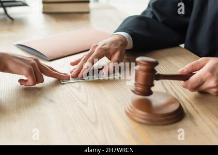 vista parziale del giudice che prende la tangente dal cliente mentre detiene il concetto di gavel, anti-corruzione Foto Stock