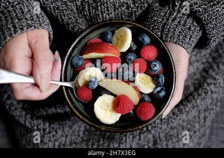 persona che tiene un recipiente rustico pieno di frutta sana per la colazione Foto Stock