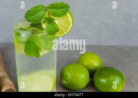 Bicchiere da cocktail Mojito con menta e lime su sfondo grigio di cemento e calce fresca. Acqua frizzante e rinfrescante. Luogo per il testo Foto Stock