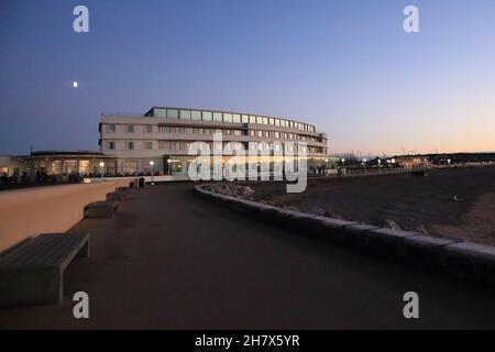 Luna e vista dell'iconico art deco Midland Hotel (progettato da Oliver Hill) dal molo al tramonto in autunno dalla spiaggia, Morecambe, Lancashire Foto Stock