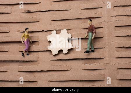 pezzo di puzzle e minuscola figurina di uomo e donna miniatura modello in vista Foto Stock