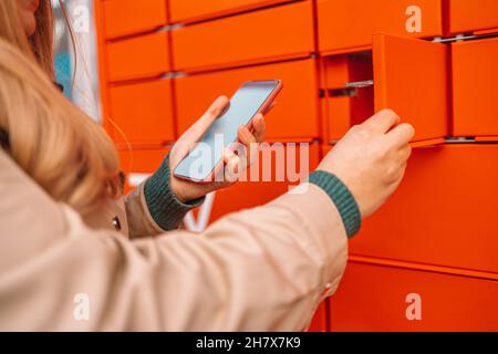 Cliente donna che utilizza un terminale automatico self-service o un armadietto. Concetto di spedizione della posta Foto Stock