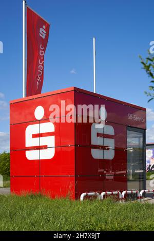 Donzdorf, Germania - 23 maggio 2021: SB-punto di servizio dalla banca (Sparkasse). L'edificio rosso a forma di cubo con bandiera è utilizzato per prelevare contanti e per la banca Foto Stock