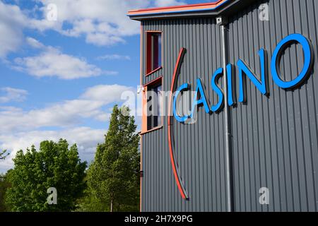 Donzdorf, Germania - 23 maggio 2021: Scritta blu da casinò sulla facciata grigia. Natura verde contro cielo nuvoloso blu. Vista laterale ad angolo basso. Foto Stock