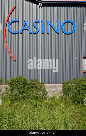 Donzdorf, Germania - 23 maggio 2021: Lettere blu del casinò sulla facciata grigia dell'edificio. Parcheggio dietro l'erba verde. Vista frontale. Foto Stock