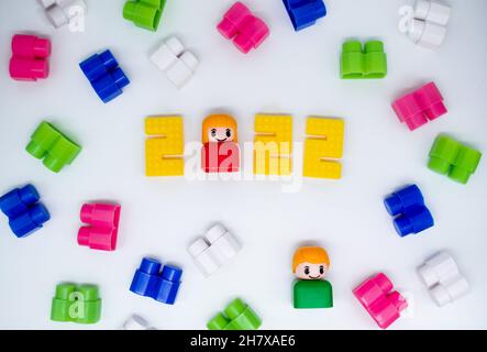 Blocchi da costruzione retrò colorati, giocattoli figure in plastica: Ragazza in 2022 numeri e ragazzo verde su sfondo bianco. Foto Stock