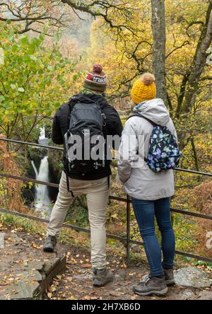 I visitatori, giovani coppie, guardano la cascata di Aira Force nel Lake District National Park, Cumbria, Inghilterra, Regno Unito, durante l'autunno o novembre Foto Stock