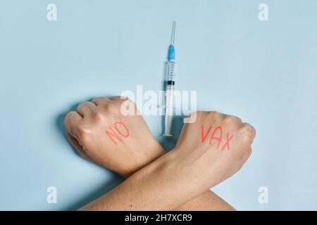 Antivaxer incrocia le mani vicino alla siringa con il vaccino Covid-19. Una persona che rifiuta l'immunizzazione contro il coronavirus. Concetto di scetticismo del Covid Foto Stock