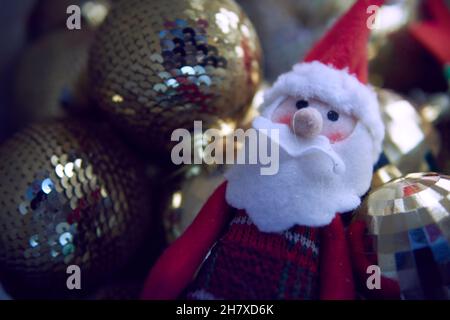 Giocattolo di Capodanno babbo natale con palle scintillanti dorate sullo sfondo. ornamenti di natale Foto Stock