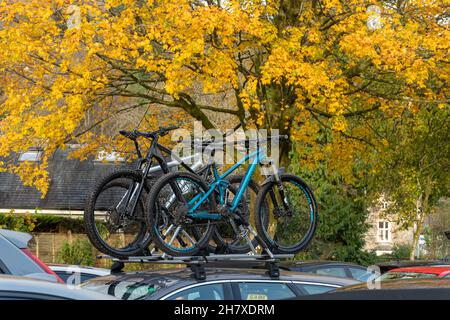 Biciclette in un rack su un tetto auto in un parcheggio affollato ad Ambleside nel Lake District National Park durante il mese di novembre con colori autunnali, Cumbria UK Foto Stock