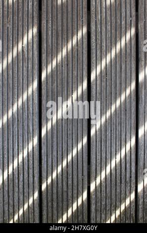 I raggi solari creano un motivo di linee sul pavimento in legno Foto Stock