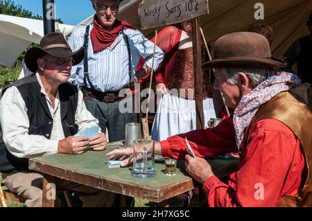 Ricreazione di un gioco di carte dell'epoca dei "cowboy" del selvaggio West USA. Rievocazione del West americano. Carte, bicchierino sul tavolo delle carte Foto Stock