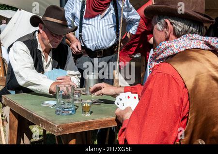 Ricreazione di un gioco di carte dell'epoca dei "cowboy" del selvaggio West USA. Rievocazione del West americano. Carte, bicchierino sul tavolo delle carte Foto Stock