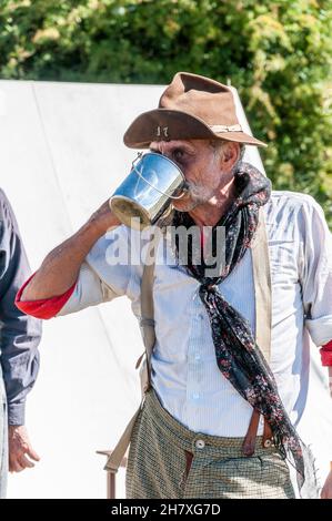 Ricostruzione dell'epoca dei "cowboy" del selvaggio West negli Stati Uniti. American West Enactment. Haggard volto del veterano americano bianco, attore, bevente Foto Stock