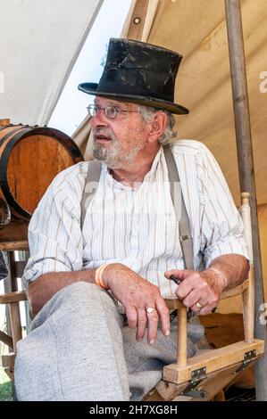 Ricostruzione dell'epoca dei "cowboy" del selvaggio West negli Stati Uniti. American West Enactment. Maschio caucasico bianco anziano in tenda, indossando un cappello d'epoca Foto Stock