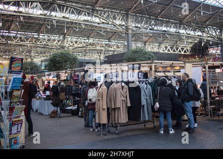 Londra, UK novembre 2021, la gente sceglie i cappotti al vecchio mercato famoso del progettista Spitalfields Market Foto Stock