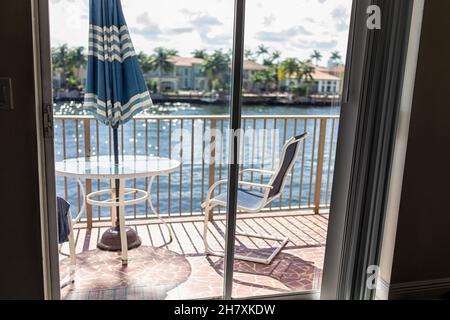 Tavolo di vetro e ringhiera nessuno sul terrazzo del balcone e ombrello blu fuori a Hollywood Beach, a nord di Miami, Florida con sedie e vista dell'acqua Foto Stock