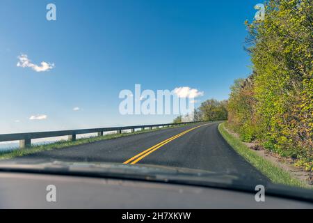 Auto pov punto di vista guidare su strada tortuosa attraverso il parabrezza in Blue Ridge Mountains parkway in Virginia con strada asfaltata e cielo blu Foto Stock