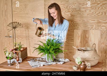 Primo piano mani di Donna innaffiare una felce, una casa. Concetto di giardino di casa. Negozio di fiori e giardini Foto Stock