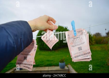 Donna appende i biglietti della lotteria sulla linea di lavaggio con sfondo naturale. Foto Stock
