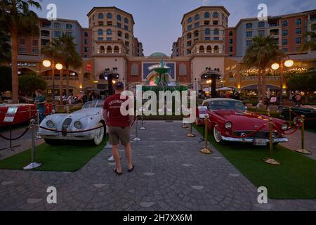 Medina Centrale nel Peral Doha, il tramonto del Qatar mostra Souq Almedina sullo sfondo con fontana illuminata in primo piano e auto classiche Foto Stock