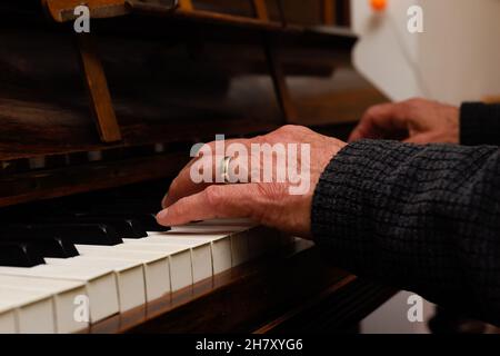 Mani mature maschili che suonano pianoforte con focus su mani e tastiera Foto Stock