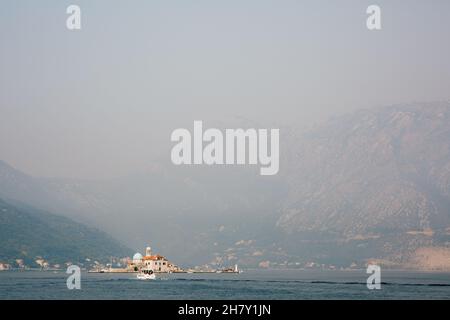 Chiesa di nostra Signora sulle rocce sullo sfondo di montagne nella nebbia. Montenegro Foto Stock